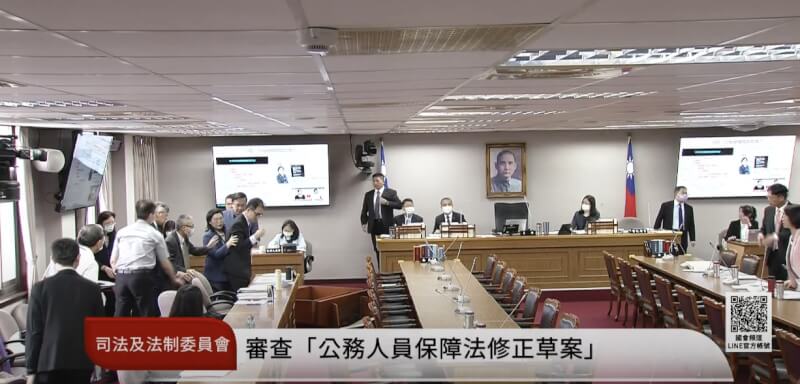 考試院秘書長劉建忻(被攙扶者)5日備詢時突暈眩,整個人往前傾倒將備詢台撞倒。(圖取自國會頻道 YouTube頻道網頁youtube.com)