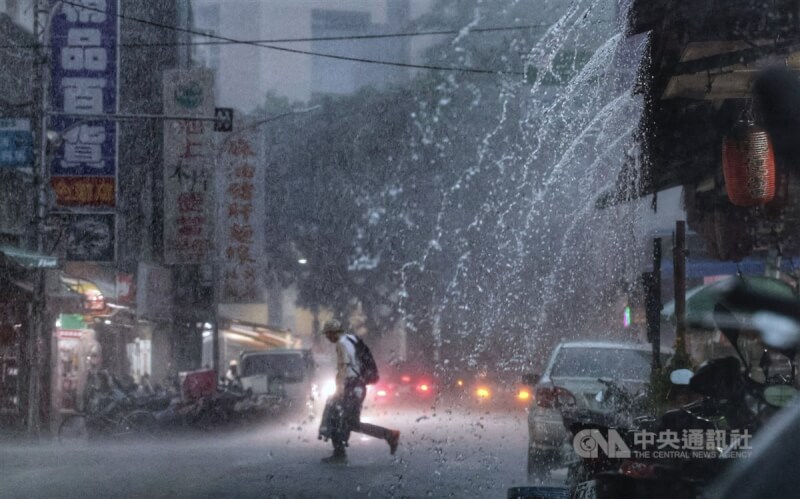 圖為台北市內湖區未帶傘具的民眾,頂著雨勢快步穿越馬路。(中央社檔案照片)