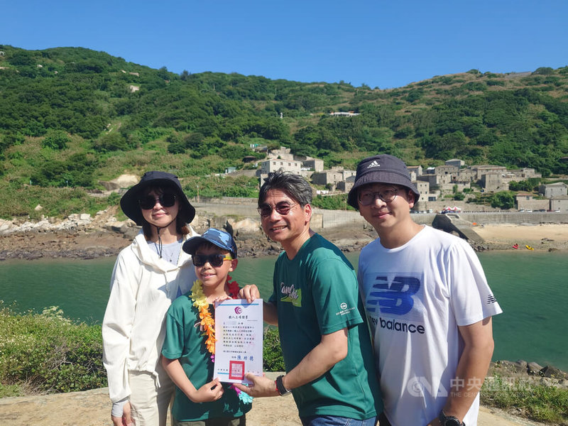 連江縣立中山國中、塘岐國小畢業生需完成鐵人三項後,登上龜島領取畢業證書,塘岐國小畢業生王熙評(左2)完成挑戰領取證書,與校長陳功德(右2)及父母開心合影留念。中央社記者潘欣彤攝 114年6月10日