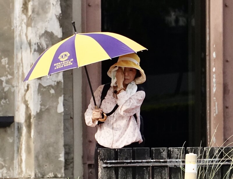 圖為高雄駁二藝術特區周邊民眾午後撐傘遮擋豔陽,頻頻拭汗。(中央社檔案照片)