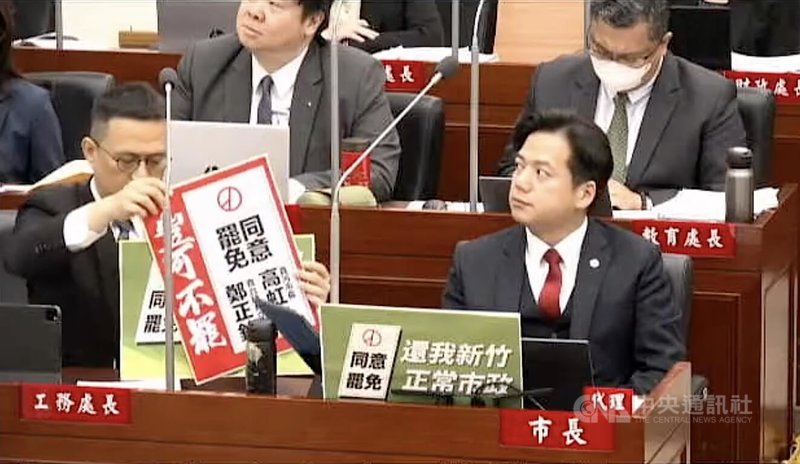 新竹市議會17日進行市政總質詢,民進黨市議員在代理市長邱臣遠(前右)座位前擺放「同意罷免」手舉牌,遭一旁工務處長陳明錚(前左)收起,引發綠議員不滿。(翻攝新竹市議會直播畫面)中央社記者魯鋼駿傳真 114年6月17日