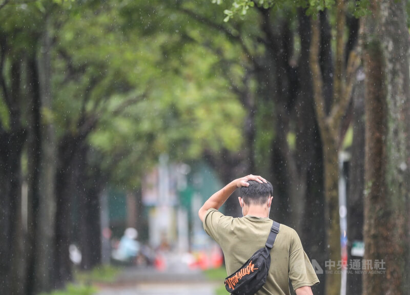 圖為台北市信義區行人以手遮雨。(中央社檔案照片)