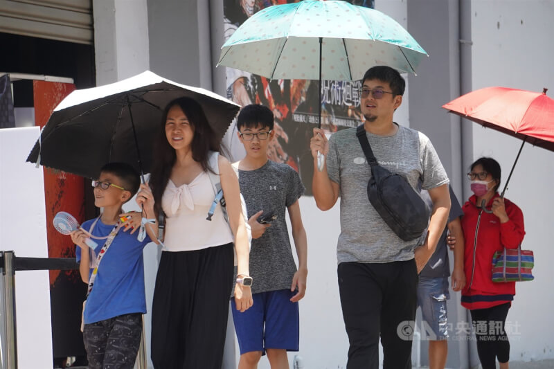 圖為民眾在高雄市鹽埕區景點撐傘遮陽。(中央社檔案照片)