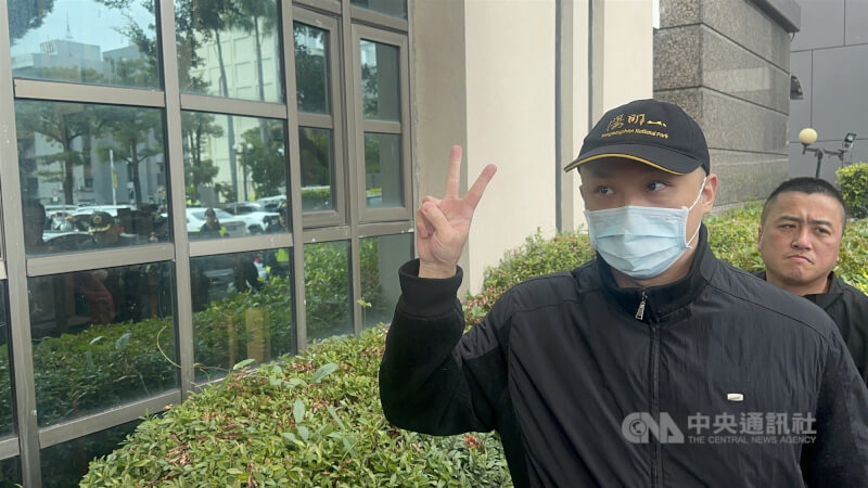圖為賴生同婚的夏男(前)被依偽造文書罪判刑,2月3日身穿黑色外套向媒體比「YA」後到地檢署報到。(中央社檔案照片)