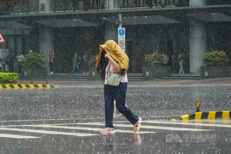 氣象署20日下午針對10縣市發布大雨特報。圖為台北市松山區未攜帶雨具的民眾以外套遮擋雨勢。(中央社檔案照片)