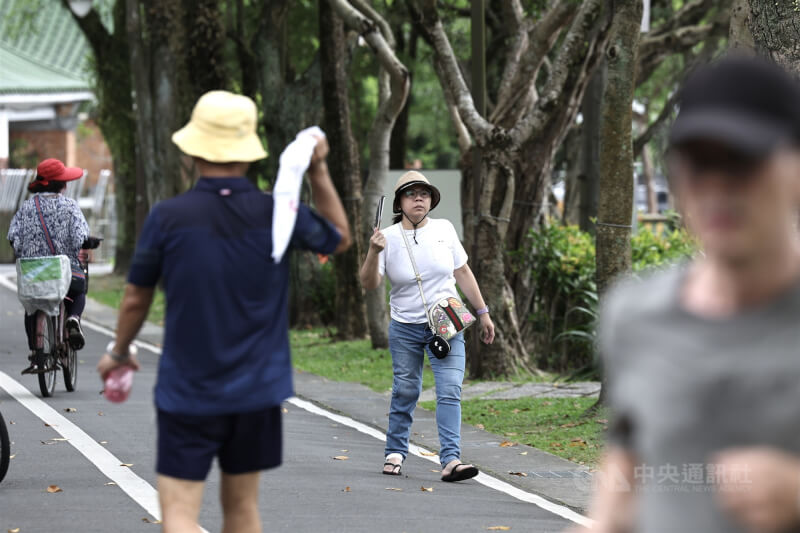 圖為台北市南港區公園內民眾戴帽拿扇子搧風。中央社記者翁睿坤攝 114年6月21日