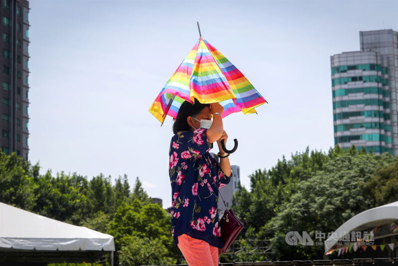 圖為台北市白天晴朗炎熱,走在中正區街頭的民眾撐傘遮陽。(中央社檔案照片)