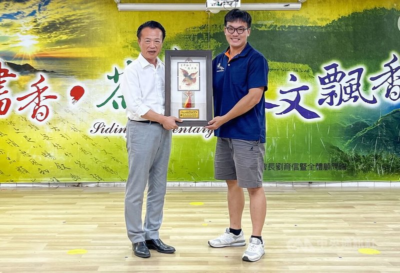 嘉義縣114年度大阿里山茶區清香烏龍茶製茶技術競賽在番路鄉隙頂舉行,24日揭曉結果,茶農李柏蒼(右)手製茶葉香氣層次分明、榮獲冠軍,由縣長翁章梁(左)頒發優勝獎牌。中央社記者蔡智明攝 114年6月24日