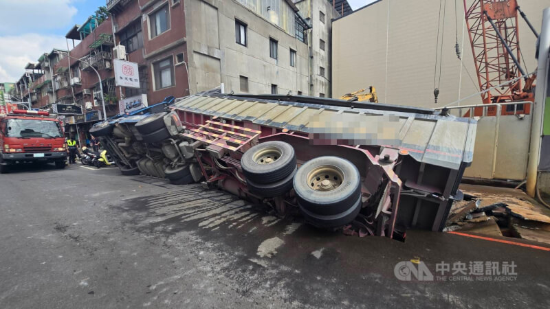 新北市三重區龍門路一處工地前路面26日塌陷,造成一輛停放路旁的砂石車側翻,消防獲報前往救援,幸無人受傷。(翻攝畫面)中央社記者趙敏雅傳真 114年6月26日