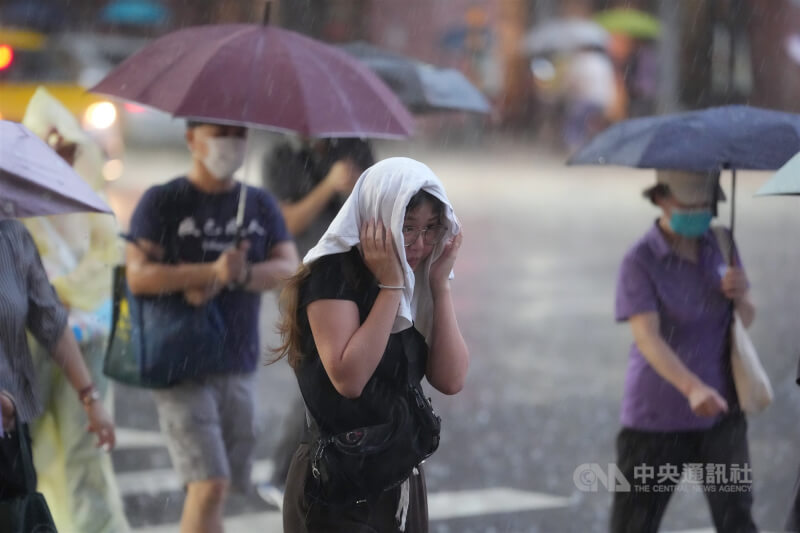 台北市中山區傍晚下大雨,民眾紛紛撐起雨傘走避,也有人以衣服遮擋頭部。(中央社檔案照片)