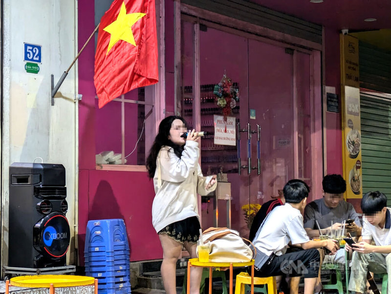 越南民眾在戶外透過擴音設備K歌產生的噪音常導致鄰里關係緊張,胡志明市過去一年半已收到超過2萬件噪音投訴。圖為一名越南民眾拿著麥克風在人行道上唱歌。中央社記者陳家倫河內攝 114年6月27日