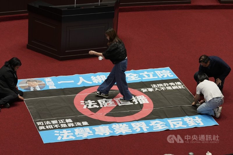 民眾黨立法院黨團27日在立法院會提案變更議程,要求27日審議涉及是否開放法庭直播的法院組織法草案,民進黨立法院黨團批評不應把法庭當直播秀場,遂行特定個案全民公審的政治意圖,要求立法院長韓國瑜應出面協商,反對倉促修法。圖為綠委在立法院議場貼海報表達訴求。中央社記者徐肇昌攝 114年6月27日