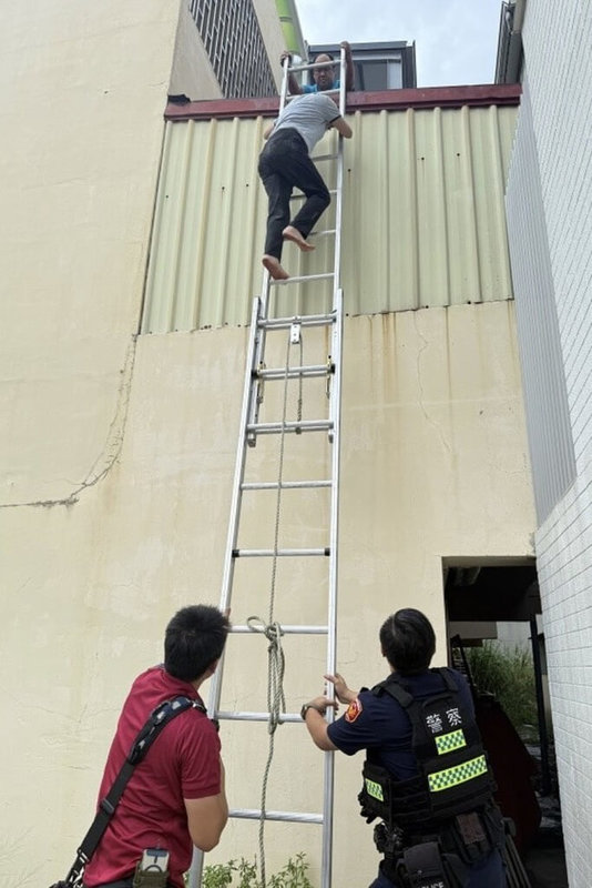 台南一婦人5日下午進行防颱檢查時,不慎跌落屋外約3層樓高鐵皮屋頂,鄰居一女童聽見呼救聲報警,警消人員架梯協助婦人脫困。(台南市警察局第四分局提供)中央社記者楊思瑞台南傳真 114年7月6日