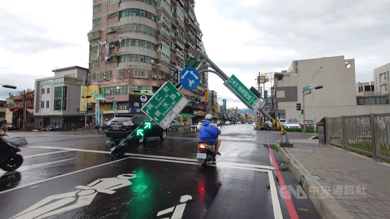颱風丹娜絲襲台為嘉義帶來強烈風雨,7日嘉義市軍輝橋路口的紅綠燈倒伏,民眾冒險從下方騎車通過。中央社記者蔡智明攝 114年7月7日