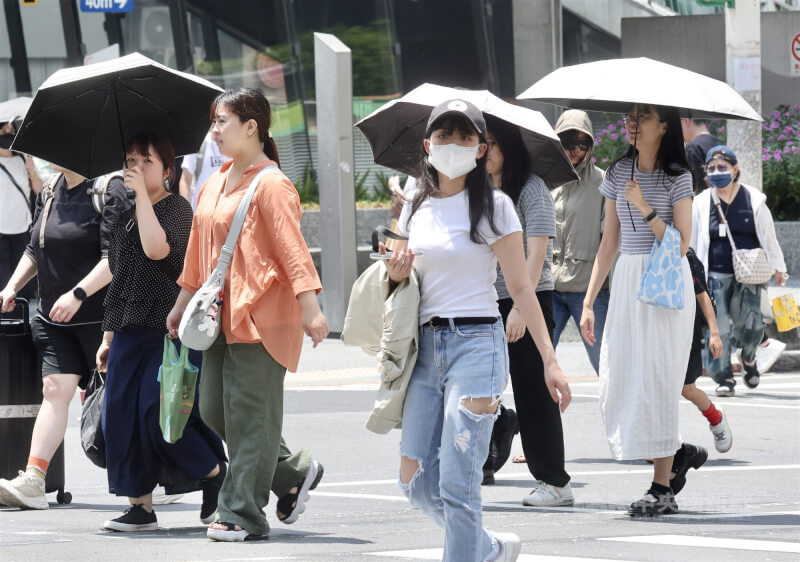 大台北、花東、金門等地8日須防範攝氏36度以上高溫。圖為台北市中山區民眾戴帽、撐傘遮陽。（中央社檔案照片）
