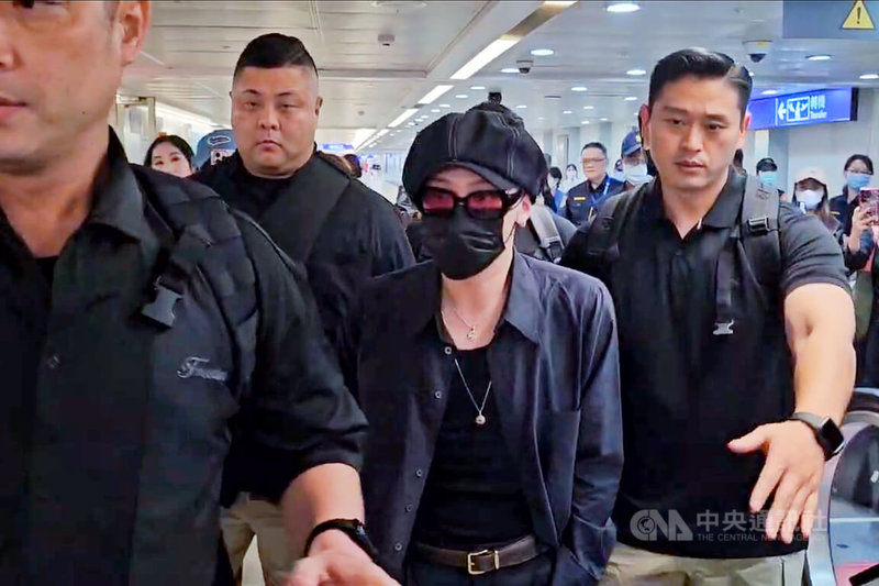南韓天王GD權志龍(G-Dragon)(右2)訪台將在台北小巨蛋開唱,10日傍晚搭機抵達桃園國際機場,全身上下都是黑色系裝扮,態度低調,在隨行人員陪同下搭車離去。中央社記者吳睿騏桃園機場攝 114年7月10日