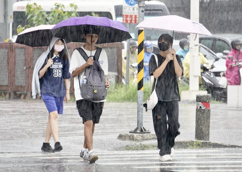 氣象署表示,11日低壓帶將北移,雨勢向中部、澎湖與金門擴展。圖為高雄市新興區大雨,民眾撐傘遮擋雨勢。(中央社檔案照片)