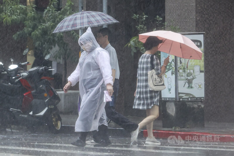 台北市中山區民眾穿上雨衣、撐傘擋雨。（中央社檔案照片）