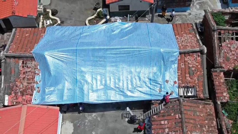 颱風丹娜絲造成嘉義縣不少弱勢家庭屋頂受損,消防局整合人力與資源組成復原任務小組協助復建,17日為布袋受損民宅屋頂覆蓋帆布。(嘉義縣消防局提供)中央社記者蔡智明傳真 114年7月17日