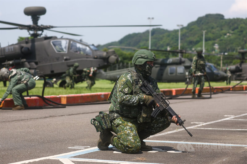 AH-64E阿帕契攻擊直升機(後)在地面進行掛彈操演,現場部署官兵在前方持槍戒備。中央社記者王騰毅攝 114年7月17日