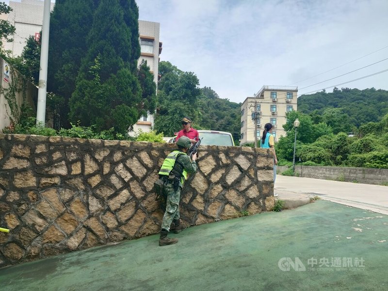 連江縣2025城鎮韌性(防空)演習18日登場,馬防部官兵全副武裝,於警報響起後在指定疏散處所、馬祖高中地下停車場前持槍保護避難民眾。中央社記者潘欣彤攝 114年7月18日