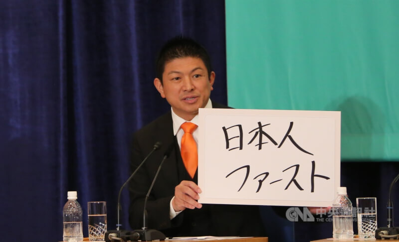日本參議院選舉將於20日投開票，外國人議題成為選戰焦點。圖為參政黨黨魁神谷宗幣2日出席在日本記者俱樂部主辦的辯論會，舉出寫著「日本人優先」的政見牌。中央社記者楊明珠東京攝　114年7月19日