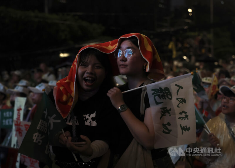 晚間雨勢忽大忽小,參與民眾拿起毛巾遮雨,熱情不減。中央社記者趙世勳攝 114年7月24日