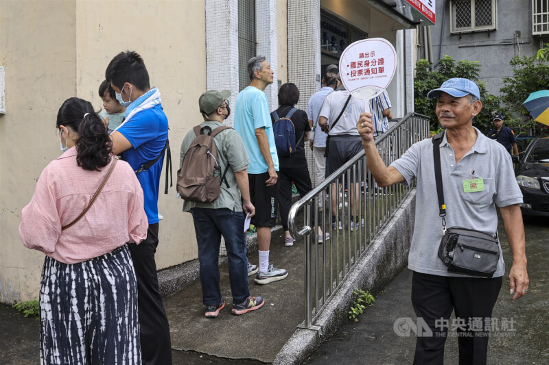 台北市文山區投票所工作人員在民眾排隊時,舉牌提醒民眾遵守投票相關規定。中央社記者鄭清元攝 114年7月26日
