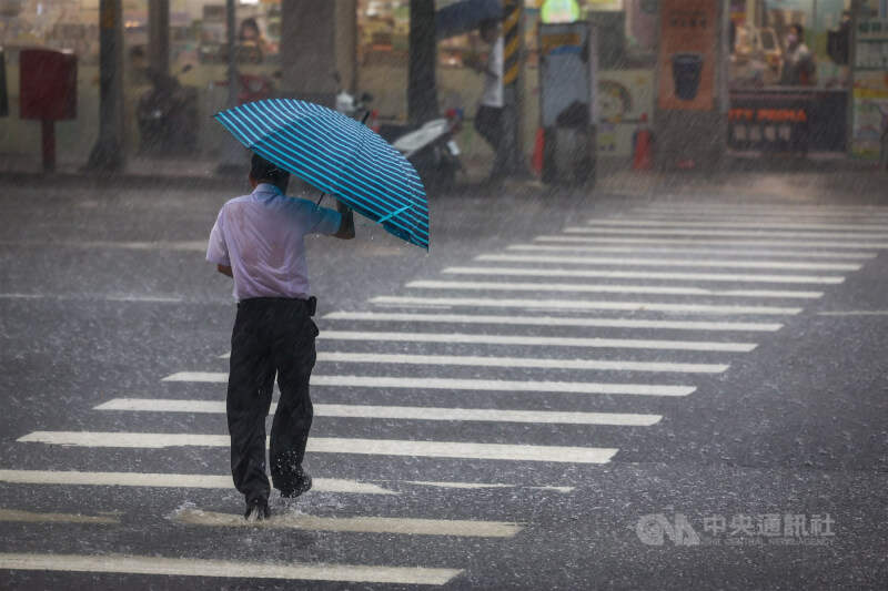 圖為新北市午後下起大雨，民眾撐傘仍擋不住雨勢。(中央社檔案照片）