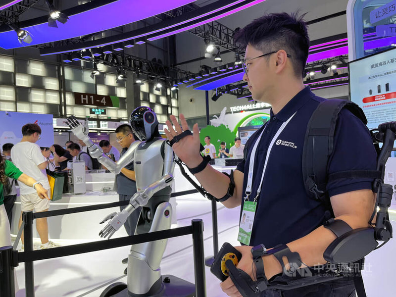 2025人工智能大會展區設在世博展覽館,一家深圳廠商展出的人形機器人隨著旁邊操控的工作人員做出揮手動作。中央社記者李雅雯上海攝 114年7月28日