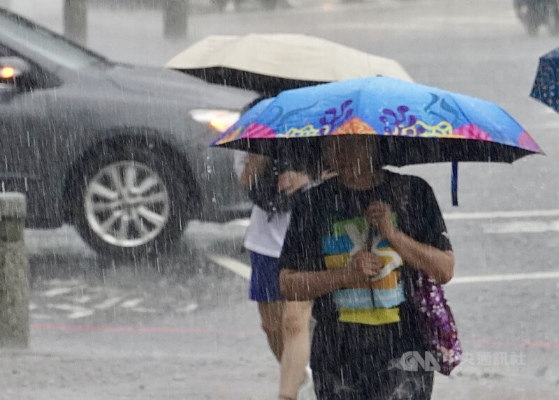 圖為高雄市民眾撐傘遮擋雨勢。（中央社檔案照片）