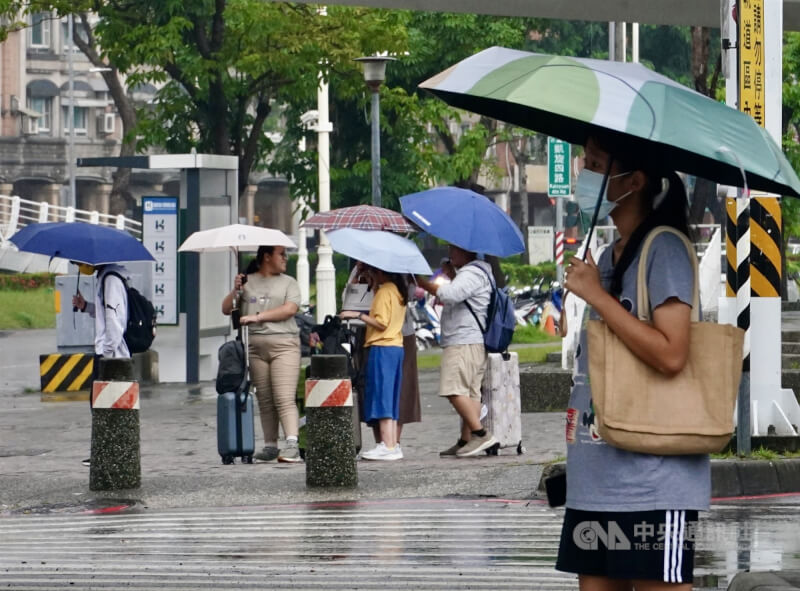 高雄市、屏東縣部分地區宣布30日停班停課。圖為高雄市前鎮區民眾撐傘遮擋雨勢。(中央社檔案照片)