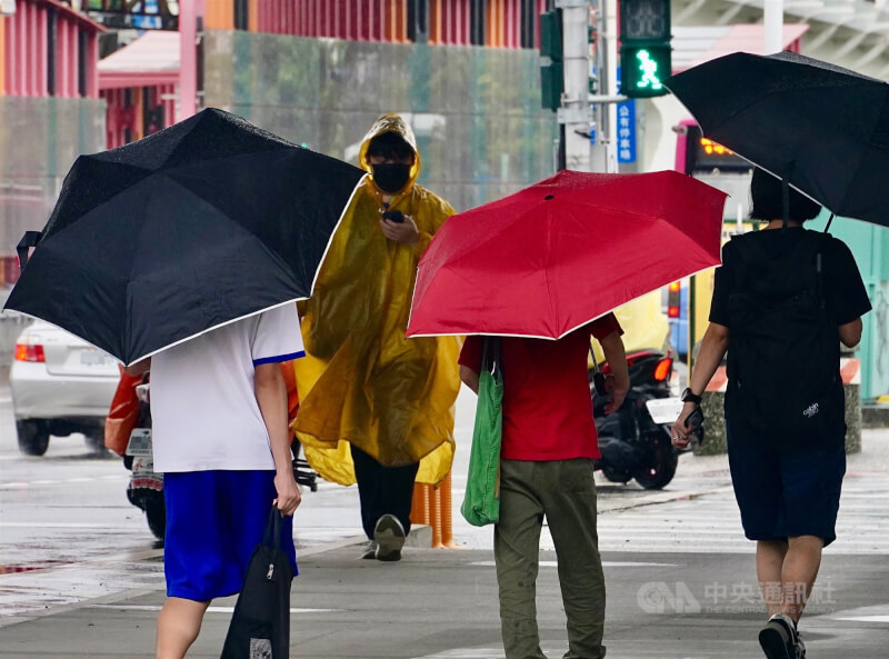 圖為高雄市前鎮區民眾穿起雨衣、撐傘過馬路。（中央社檔案照片）