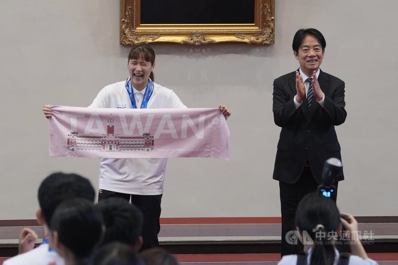 總統賴清德(右)31日在總統府接見「2025年第32屆萊茵魯爾夏季世界大學運動會代表團」選手、教練及隊職員,贈送紀念品給羽球混雙金牌選手楊筑云(左)。中央社記者徐肇昌攝 114年7月31日