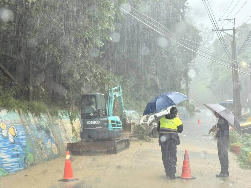 連日降雨導致山坡含水過飽，台中市潭子區龍興巷發生邊坡土石滑落事故，大量泥沙與倒伏樹木堵塞道路，警方冒雨支援清除障礙。（警方提供）中央社記者趙麗妍傳真　114年8月1日