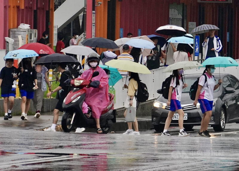 圖為高雄市前鎮區出現雨勢,過馬路民眾紛紛撐起雨傘。(中央社檔案照片)
