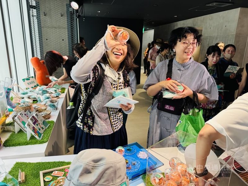 「We TAIWAN台灣文化in大阪.關西世博」2日在日本大阪起跑,「台灣光譜」上午開展前吸引排隊人潮,原來都是為了搶購吉祥物a-We周邊商品。民眾拿起玻璃紙鎮扭蛋,仔細觀察,希望抽中想要的顏色。中央社記者楊明珠大阪攝 114年8月2日