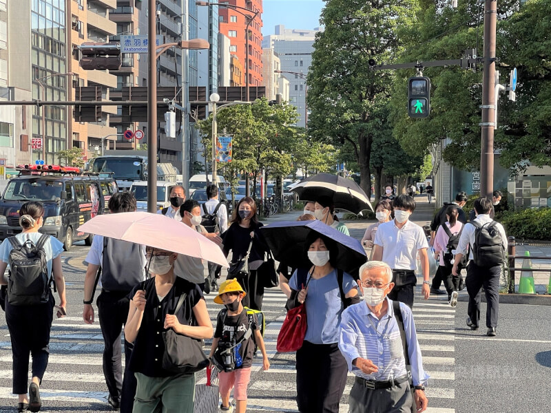 圖為東京市街頭民眾撐傘戴帽遮陽。(中央社檔案照片)