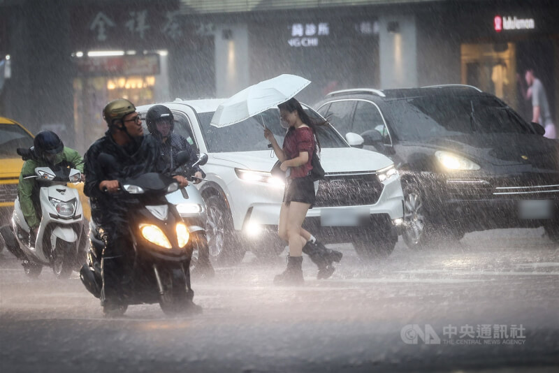 圖為民眾在滂沱大雨中，撐傘穿過路口。（中央社檔案照片）