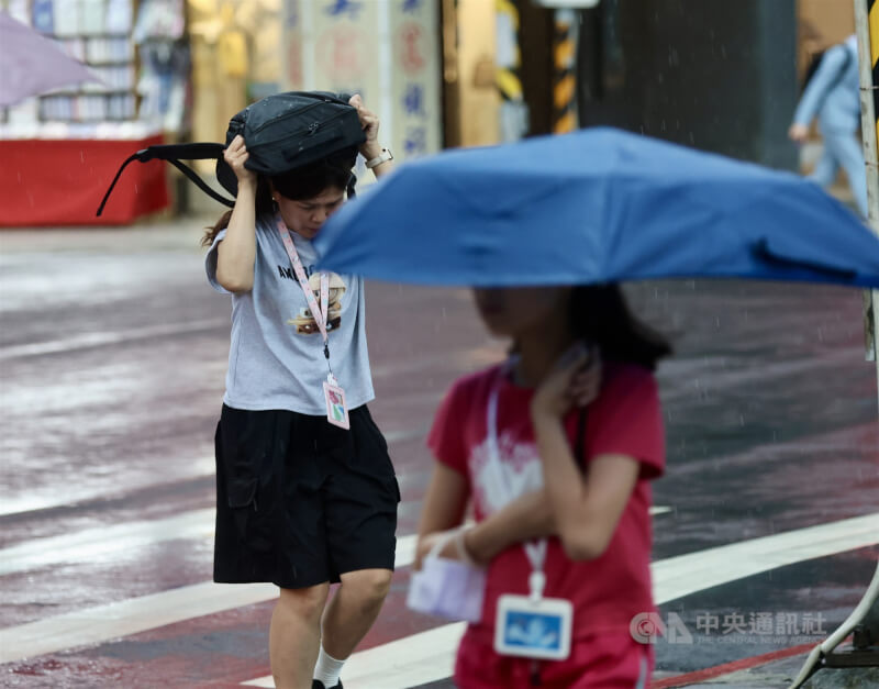 圖為台北市中正區街頭有民眾用包包遮雨，快步過馬路。（中央社檔案照片）