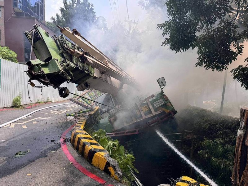 32歲林姓吊車駕駛6日開車行經台北市北投區溫泉路附近，發現車輛不明原因冒出濃煙，決定跳車但因情況緊急未拉手煞車，導致吊車滑落邊坡。（警消提供）中央社記者劉建邦傳真  114年8月6日