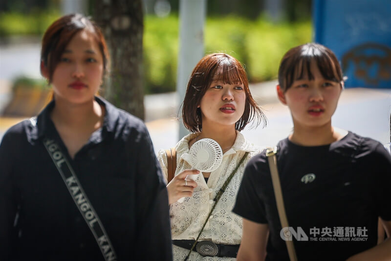 圖為炎熱的天氣下，北市中正區民眾隨身帶電扇降溫。（中央社檔案照片）