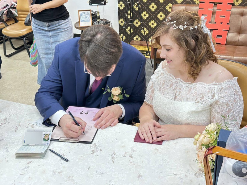 一對德國新人14日在台南市中西區戶政事務所填寫結婚登記資料,新郎Martin(左)一筆一畫寫下觀光署協助翻譯而取的中文名字。(觀光署法蘭克福辦事處提供)中央社記者林尚縈柏林傳真 114年8月15日