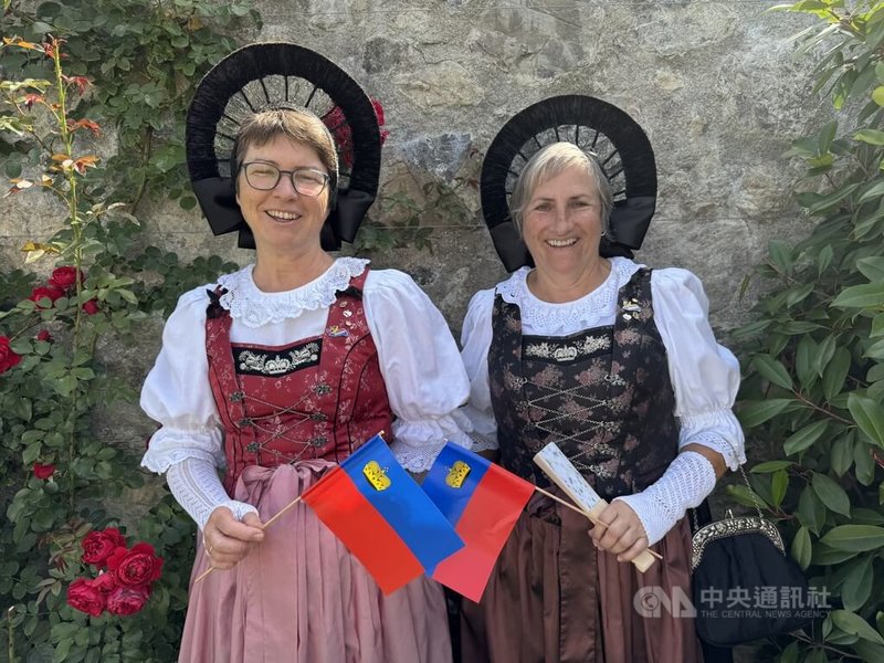 列支敦斯登當地民眾身著傳統服飾,手持國旗,參與城堡花園酒會。 中央社記者郭芳君列支敦斯登攝 114年8月15日