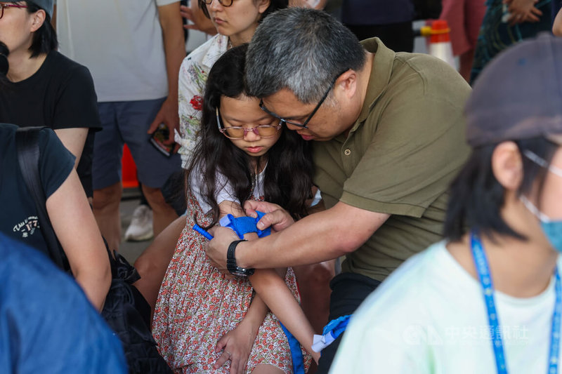 黑熊民防教育協會表示,「不止一命:止血帶街頭挑戰」以教導民眾止血帶操作技能為核心,提升自救與互救能力,活動17日在台北捷運圓山站外舉行。圖為小朋友與家長學習使用止血帶。中央社記者吳家昇攝 114年8月17日
