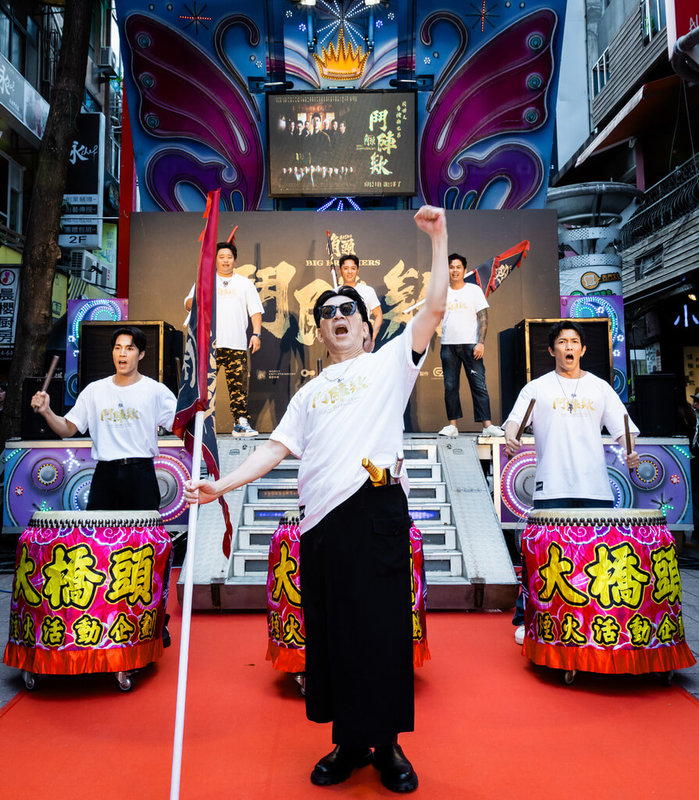 「角頭-鬥陣欸」19日在西門町舉辦活動,演員高捷(中)舉大旗,其他演員擊鼓,祈求票房創佳績。(曼尼娛樂提供)中央社記者王心妤傳真 114年8月20日