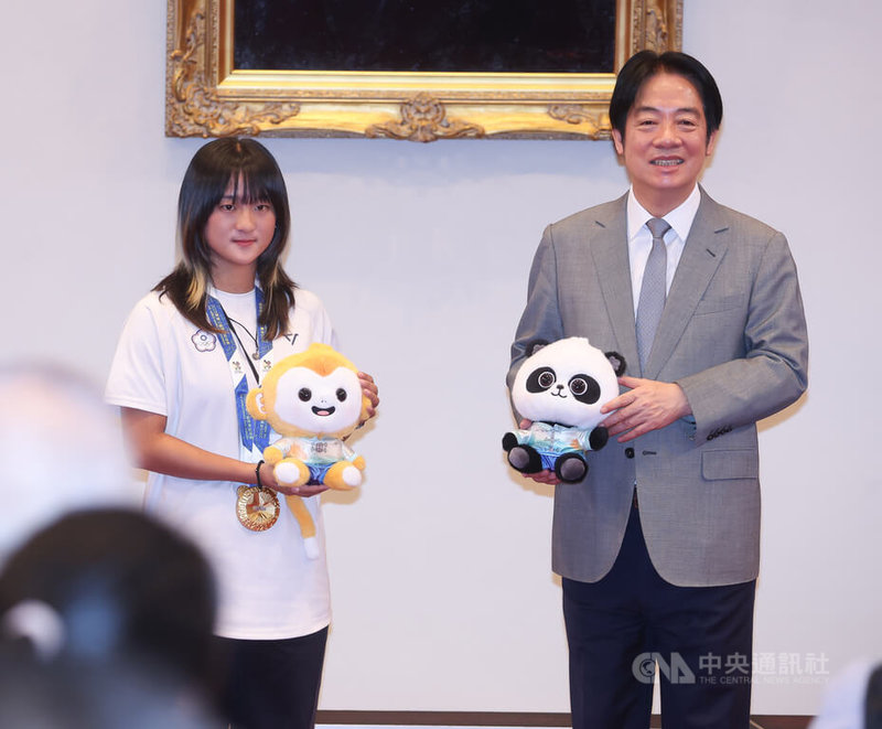 總統賴清德(右)21日在總統府接見「2025年第12屆成都世界運動會」代表團,滑輪溜冰選手劉巧兮(左)代表致贈賴總統世運會吉祥物。中央社記者謝佳璋攝 114年8月21日