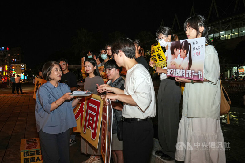 核三重啟公投在即,屏東青年22日晚間在屏東火車站前舉「核三重啟不同意」等字牌,進行公民短講,縣長周春米(前左)送上青草茶打氣。中央社記者黃郁菁攝 114年8月22日