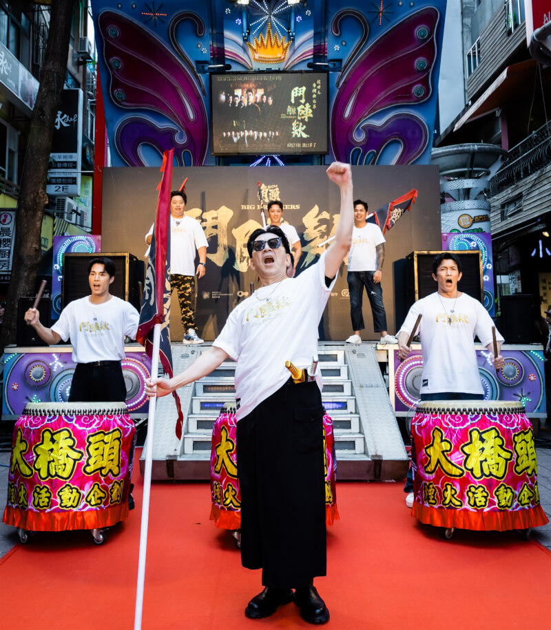 「角頭-鬥陣欸」19日在西門町舉辦活動,演員高捷(中)舉大旗,其他演員擊鼓,祈求票房創佳績。(曼尼娛樂提供)