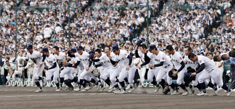 沖繩尚學23日奪得校史首座夏季甲子園冠軍,球員興奮跑進場內慶祝。(共同社)